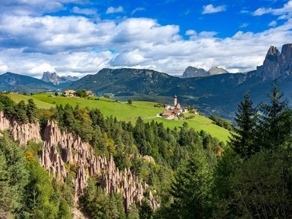 Strada del Vino dell’Alto Adige, un paradiso escursionistico Villaggio montano con piramidi di terra sulle Alpi sotto un cielo azzurro