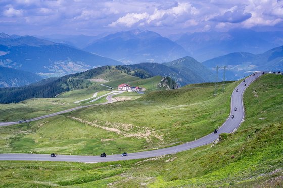 Ein Hotel furs Motorrad in Südtirol – der Hit! Gebirgsstraße mit Motorrädern und grünen Hügeln unter bewölktem Himmel