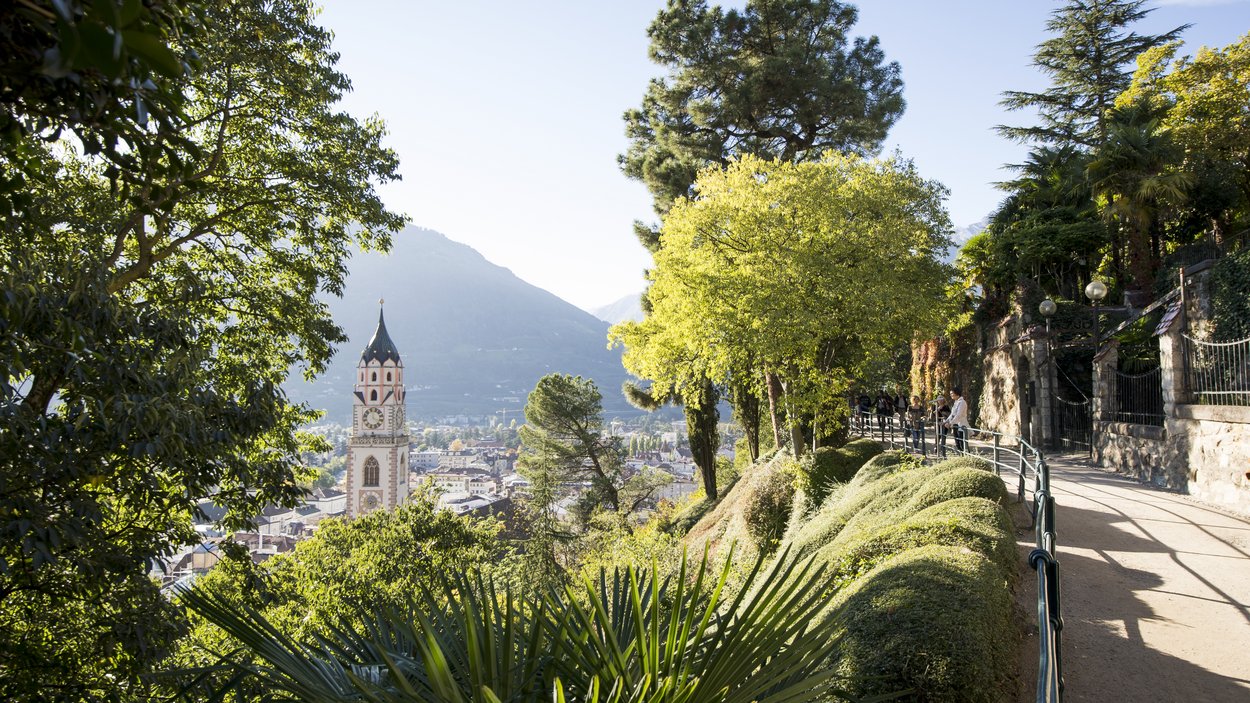 Ihre Hotels in Meran in Südtirol: Hotels im Meraner Land Wanderweg mit Blick auf Kirchturm und Stadt zwischen grünen Bäumen und Bergen