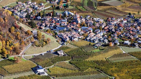 Der Sonnenberg in Naturns Luftaufnahme eines Dorfes umgeben von landwirtschaftlichen Feldern im Herbst