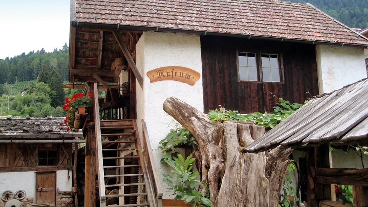 Bauernmuseum Völlan in Südtirol Altes Holzhaus mit Museumsschild und Garten in ländlicher Umgebung