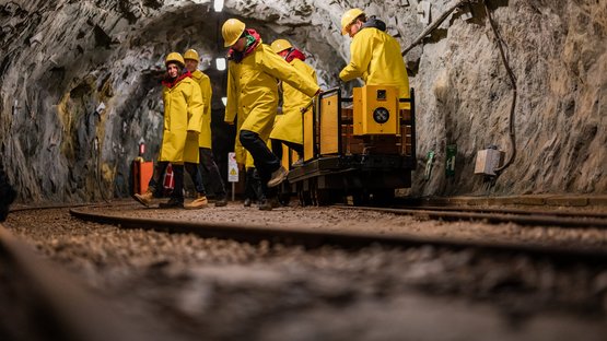 Das Bergbaumuseum in Prettau Menschen in gelben Schutzhelmen und Mänteln in einem Bergwerkstunnel