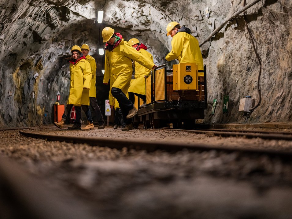 Das Bergbaumuseum in Prettau Menschen in gelben Schutzhelmen und Mänteln in einem Bergwerkstunnel