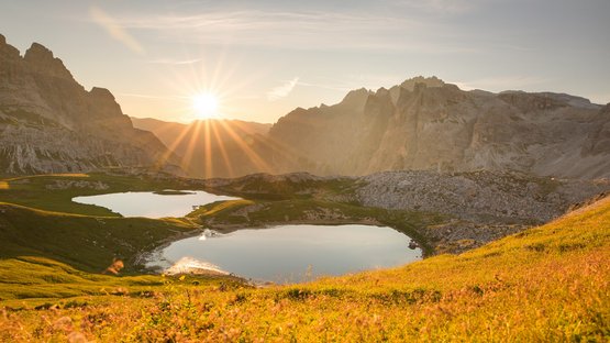 Hotel a Sesto in Alto Adige Tramonto su due laghi di montagna e prato fiorito nelle Alpi