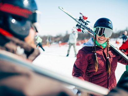 Sciare in Alto Adige: una montagna di divertimento sulle piste Sciatrice sorridente con casco e sci sulla neve in una località sciistica
