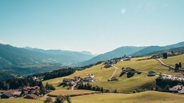 Hotels Eisacktal, Südtirol: Hotels in Brixen, Klausen … Bergdorf mit grünen Wiesen und Bergen im Hintergrund bei klarem Himmel