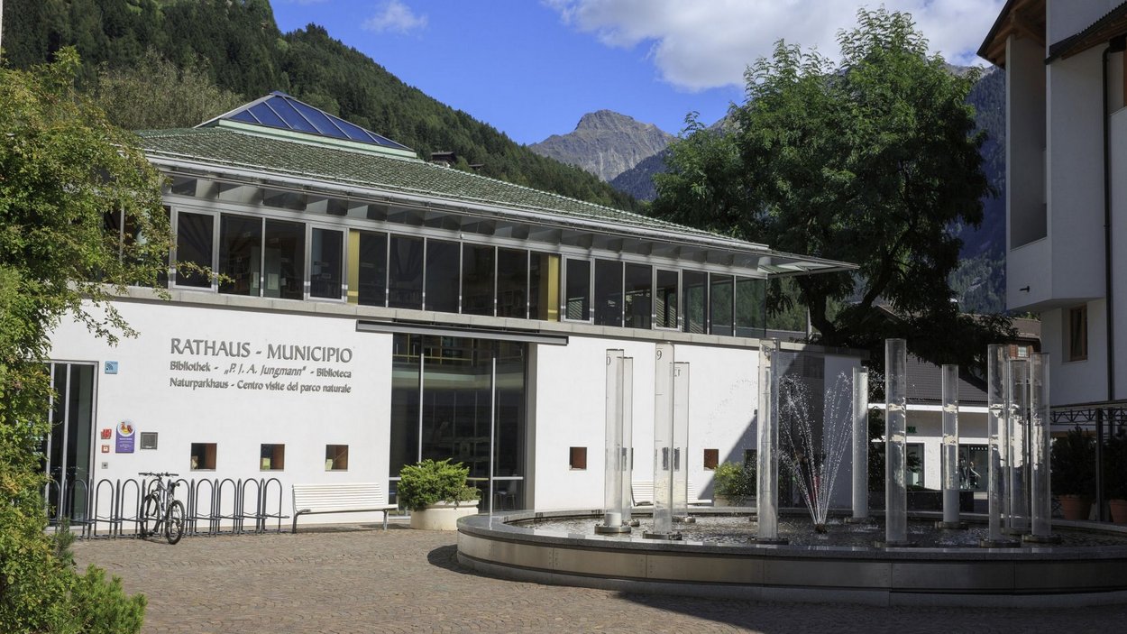 Das Naturparkhaus im Ahrntal Rathaus und Bibliothek mit Brunnen und Bergen im Hintergrund in Italien