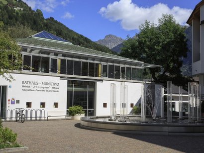 Hotel a Plan de Corones Municipio e biblioteca con fontana e montagne sullo sfondo in Italia