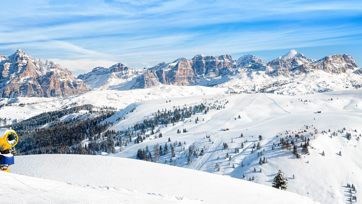 Schneespaß in Alta Badia Schneebedeckte Berge und Skipiste mit Schneekanone bei klarem Himmel
