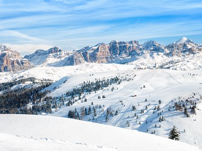 La Sellaronda, per girare attorno al massiccio del Sella Montagne innevate e pista da sci con cannone spara neve sotto un cielo limpido