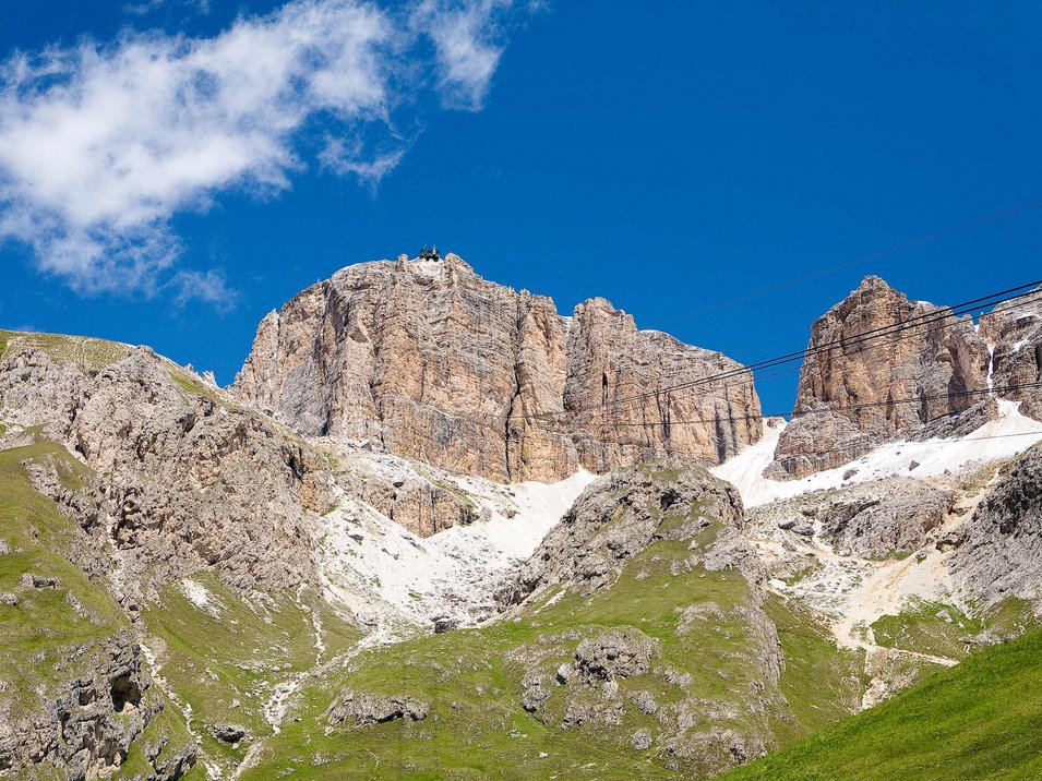 Das Grödner Joch Felsige Berge mit grünen Wiesen und blauem Himmel darunter