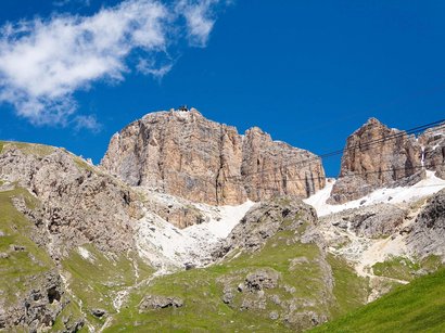 Unterwegs in den Dolomiten Felsige Berge mit grünen Wiesen und blauem Himmel darunter
