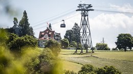 Hotel a Bolzano in Alto Adige Funivia con cabina sopra campi verdi e casa sullo sfondo