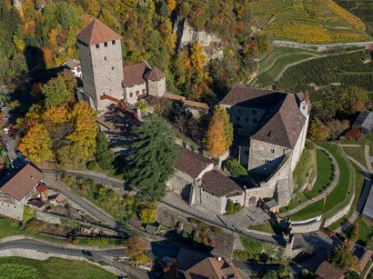 Cinema all’aperto in Alto Adige Veduta aerea di un castello con alberi autunnali e vigneti circostanti