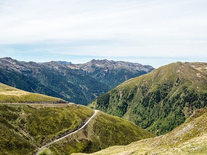 Die Hotels in Sterzing versprechen wunderbare Tage Bergstraße mit grünen Hügeln und bewaldeten Bergen unter bewölktem Himmel