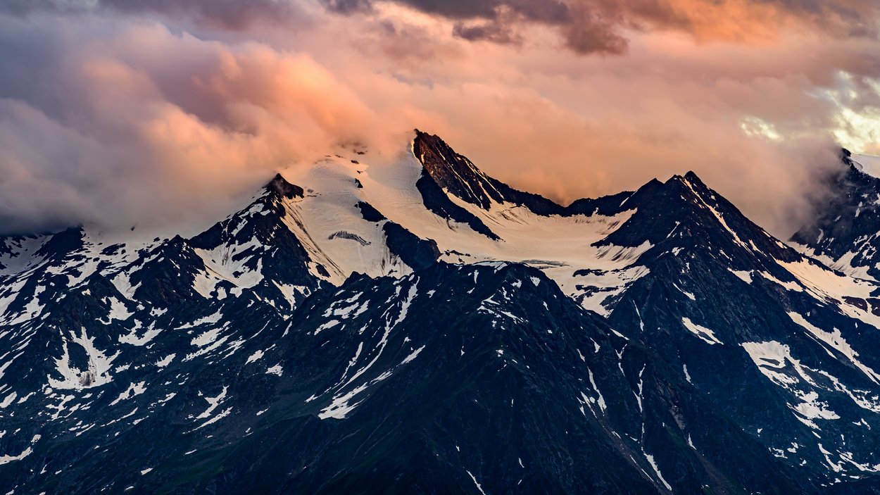 Von Südtirol nach Österreich über den Wilden Freiger Schneebedeckte Berge bei Sonnenuntergang mit Wolken am Himmel