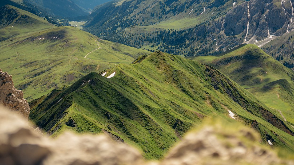 Chalets in Südtirol - Luxus & Ruhe Grüne Berglandschaft mit schroffen Felsen und Tälern im Hintergrund