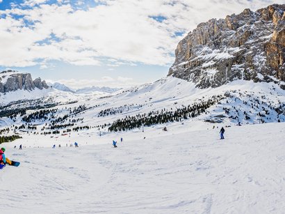 Ihr Winterurlaub im Skigebiet Sextner Dolomiten Skifahrer und Snowboarder auf verschneiter Bergpiste mit Felsen und Wolkenhimmel