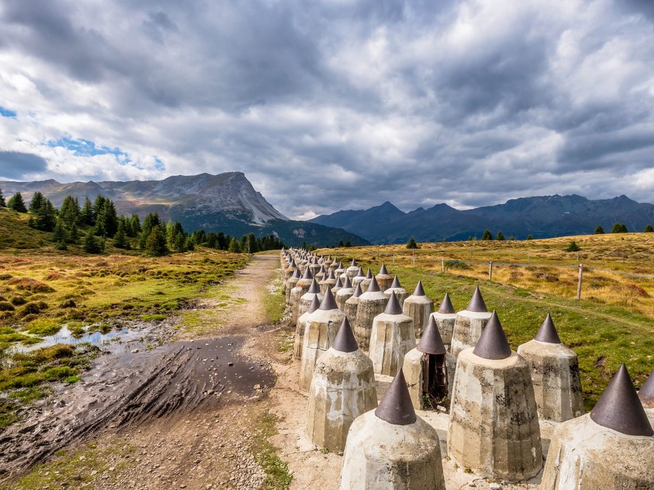 Sbarramento Valle Alpino del Littorio a Plamort Fila di fortificazioni anticarro su un sentiero di campagna nelle montagne sotto un cielo nuvoloso