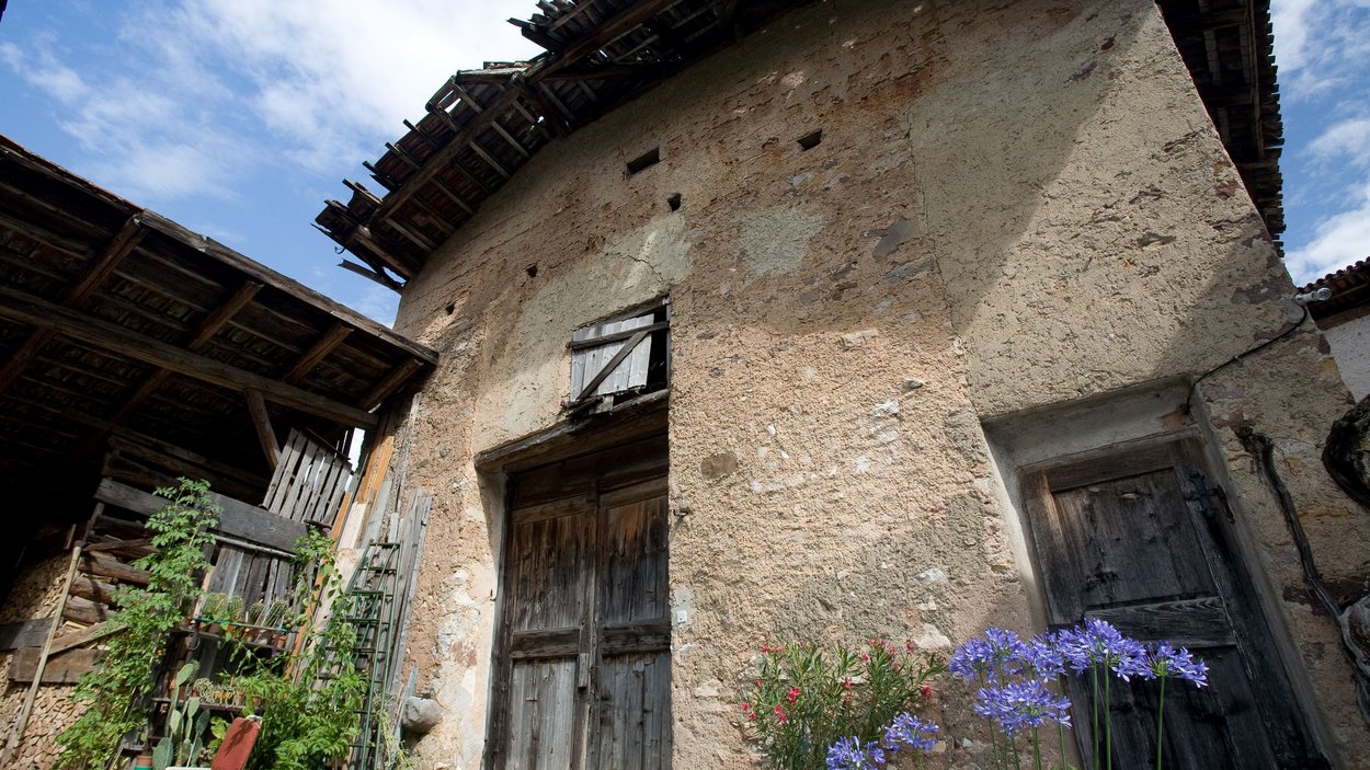 Hotel a San Leonardo in Passiria Vecchia casa rustica con porte di legno, piante e fiori blu in primo piano