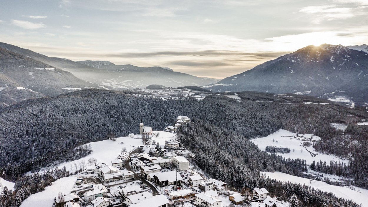Wandern auf der Rodenecker und Lüsner Alm Dorf und verschneite Wälder in einem Tal mit Bergen im Hintergrund