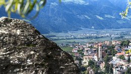 Hotels in St. Martin in Passeier: Ab in den Traumurlaub! Blick auf ein Dorf mit Kirche in einem grünen Tal vor bewaldeten Bergen