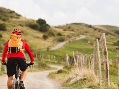 Ciclabile della Val Casies Ciclista con zaino arancione percorre sentiero in campagna collinare