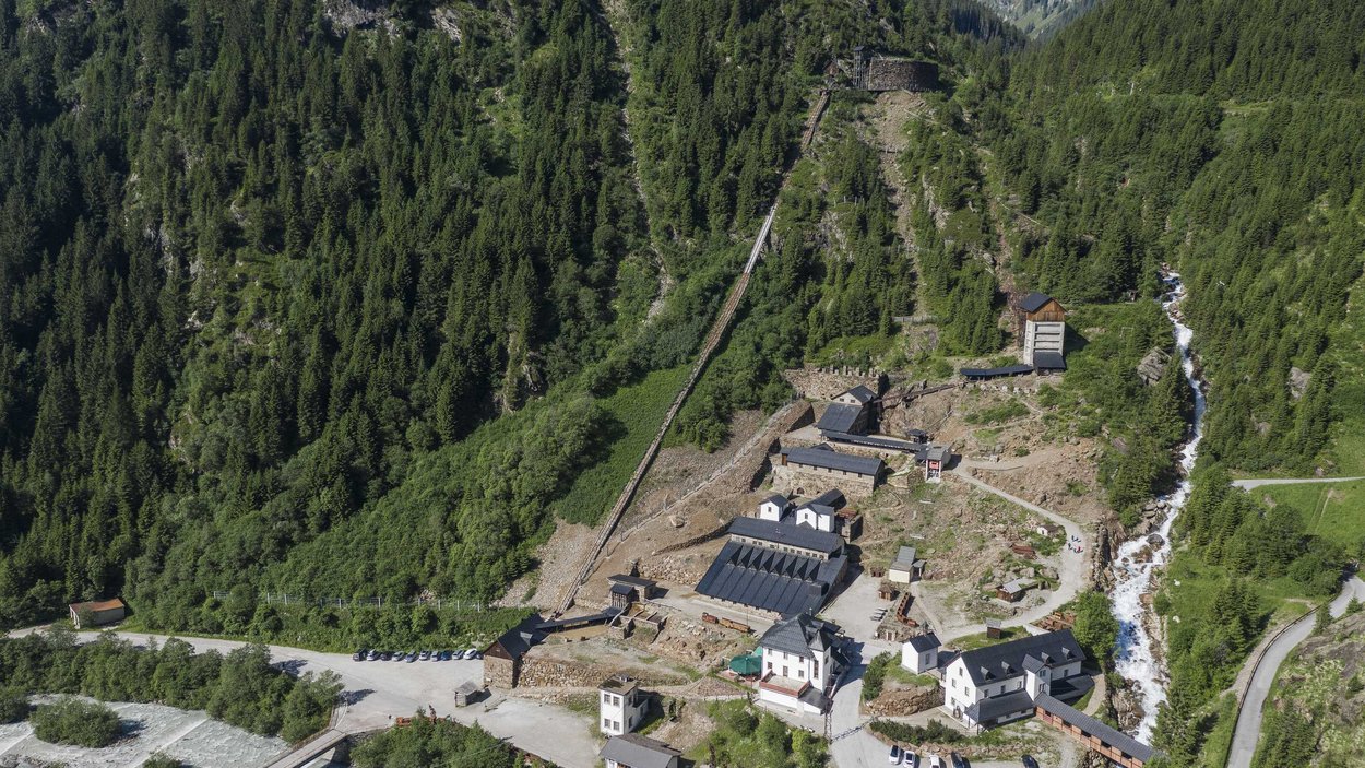 Il Museo Provinciale Miniere di Ridanna Veduta aerea di un insediamento montano con edifici, bosco e fiume nelle Alpi