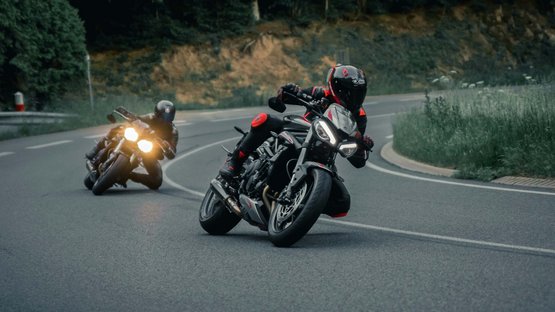 Hotel per motociclisti in Alto Adige Due motociclette che sfrecciano su una strada tortuosa circondata da alberi