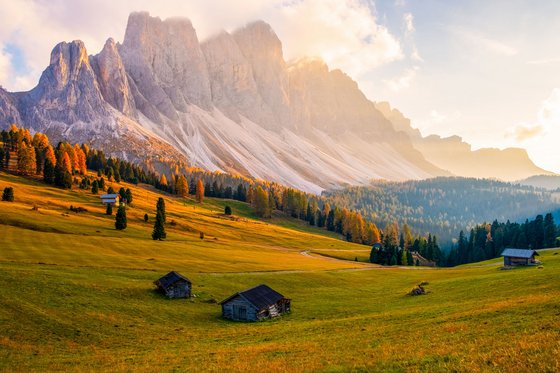 Trentino-Südtirol entdecken Herbstliche Alpenlandschaft mit Hütten und Sonnenlicht im Tal