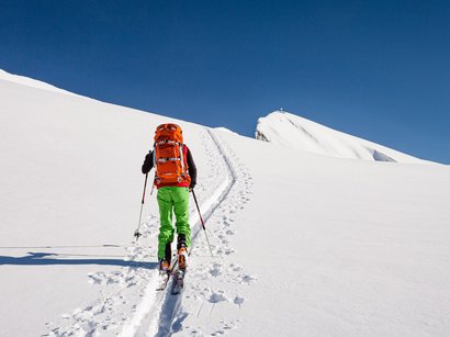 Hotel a Prato allo Stelvio Sciatore con zaino rosso e pantaloni verdi che sale sulla neve
