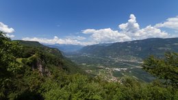 Hotels in St. Martin in Passeier: Ab in den Traumurlaub! Blick von einem bewaldeten Berg auf ein Tal mit Dörfern und Bergen im Hintergrund
