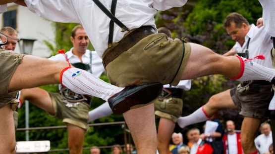 Goaslschneller e Schuahplattler Uomini che ballano in abiti tradizionali bavaresi alzano le gambe contemporaneamente