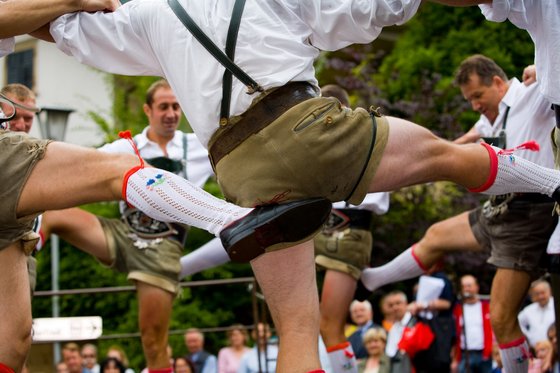 Trentino-Südtirol entdecken Tanzende Männer in traditioneller bayerischer Tracht heben die Beine gleichzeitig