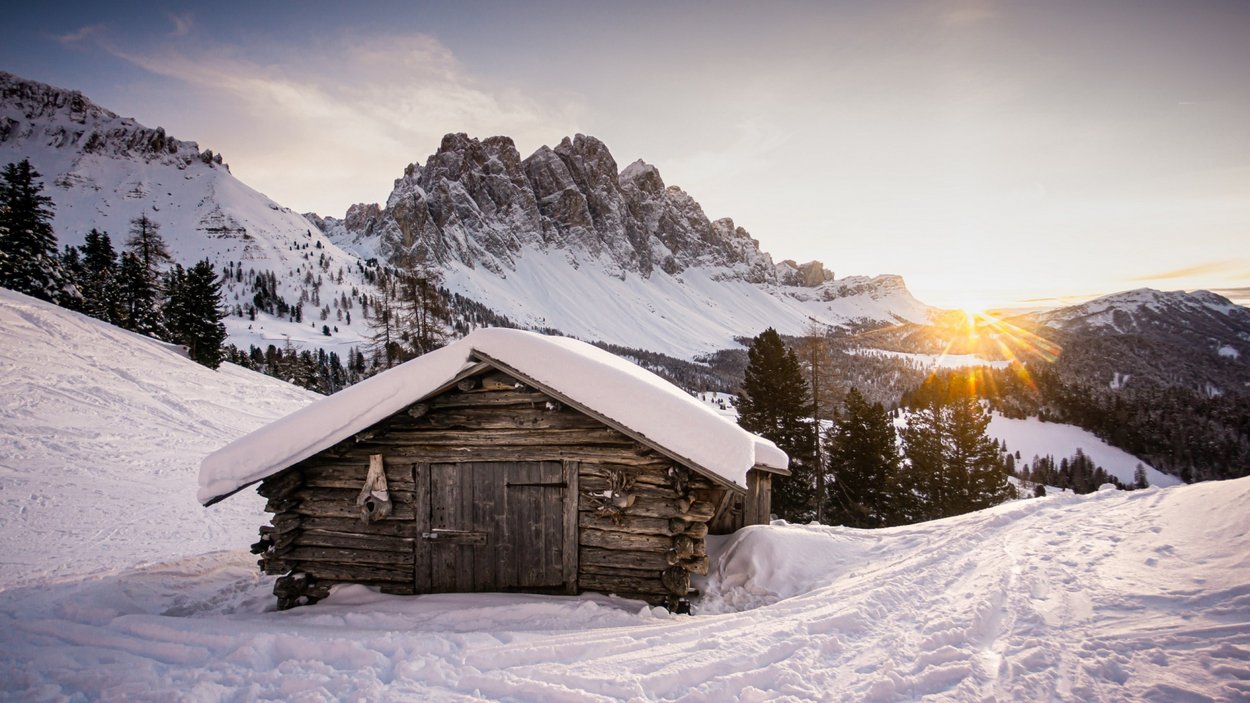 Die Geisleralm-Rodelbahn Holzhütte im verschneiten Bergland bei Sonnenuntergang