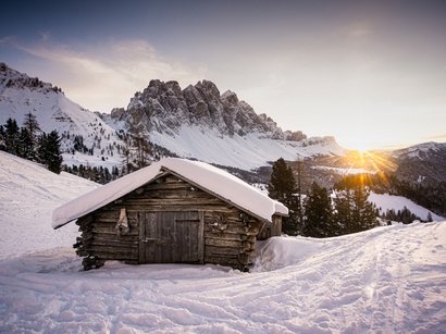 Winterwanderung von Gasteig nach Mareit Holzhütte im verschneiten Bergland bei Sonnenuntergang