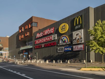 Der Mendelpass Außenansicht eines Einkaufszentrums mit verschiedenen Ladenlogos an der Fassade