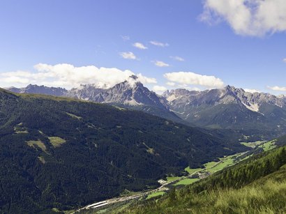 Klettersteig Michl Panoramablick auf bewaldete Berge und ein Tal unter blauem Himmel