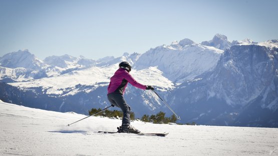 Pistengaudi am Rittner Horn Skifahrer in rosa Jacke auf verschneiter Bergpiste vor Alpenkulisse