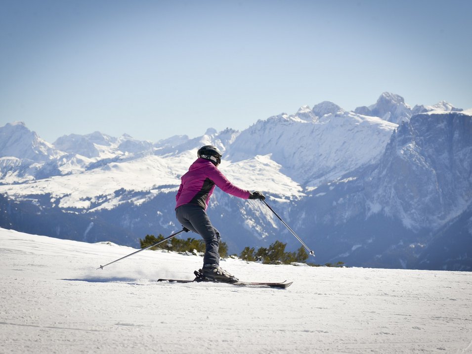 Pistengaudi am Rittner Horn Skifahrer in rosa Jacke auf verschneiter Bergpiste vor Alpenkulisse