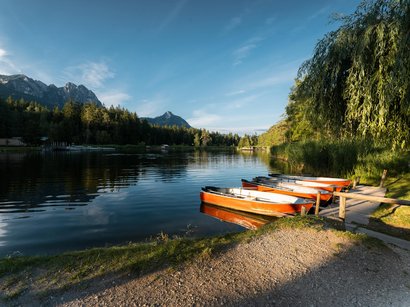 Der Pragser Wildsee im Hochpustertal in Südtirol Boote am Ufer eines ruhigen Sees mit Bergen und Wald im Hintergrund