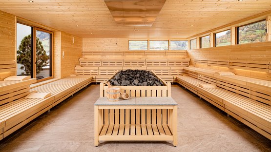 Das Sterzinger Hallenbad Großer Sauna-Raum mit Holzbänken und Kamin voller Sauna-Steine