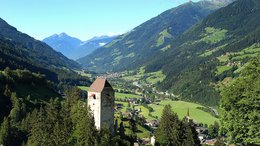 Hotel a Scena presso Merano Valle di montagna con rovine di castello e prati verdi sotto il cielo azzurro