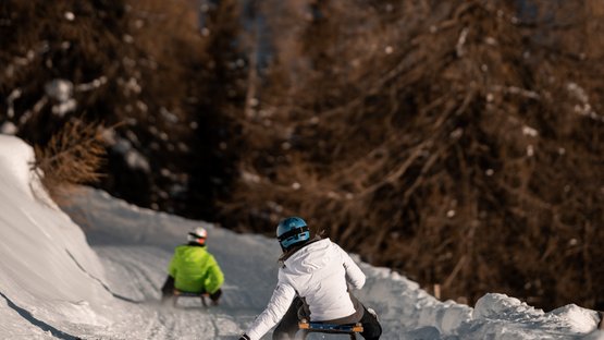 La pista da slittino più lunga dell’Alto Adige Persone che slittano su una pista innevata con montagne sullo sfondo