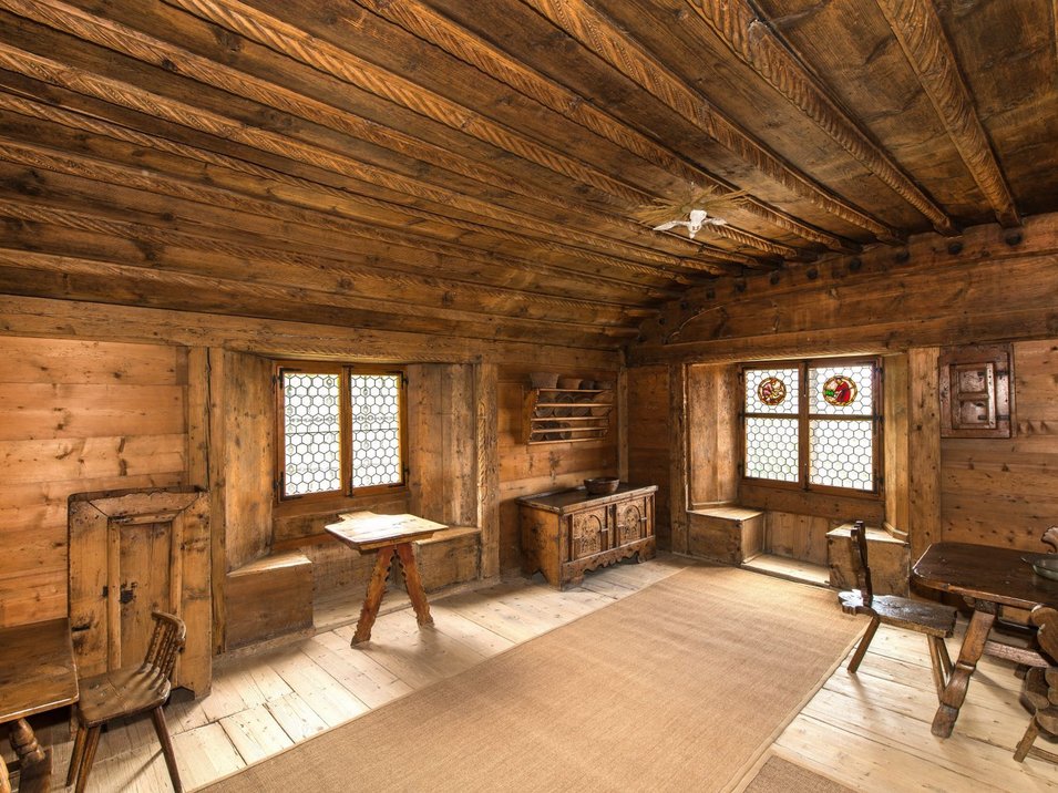 Castel Palù-Schulthaus ad Appiano Stanza rustica con mobili in legno e finestre con vetri colorati