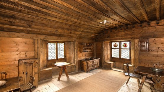 Castel Palù-Schulthaus ad Appiano Stanza rustica con mobili in legno e finestre con vetri colorati