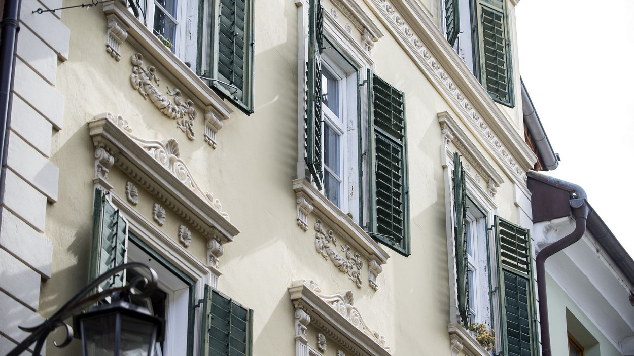 Kunst Meran – Galerie, Museum, Eventlocation Hausfassade mit gelber Wand und grünen Fensterläden in historischem Stil