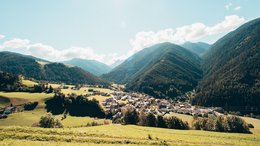Hotels Eisacktal, Südtirol: Hotels in Brixen, Klausen … Blick auf ein Dorf im Tal umgeben von Bergen und grünen Wiesen bei Sonnenschein