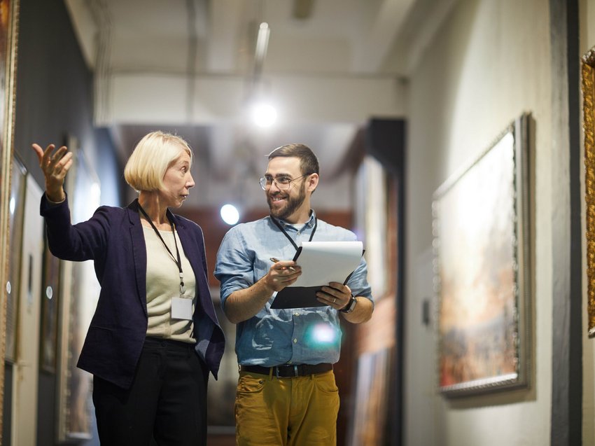 Hotel in Alto Adige 😎☀️ Per vacanze indimenticabili Due operatori museali discutono davanti a dipinti in una galleria d'arte