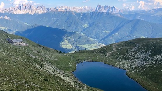 Il Lago Rodella, sopra Bressanone Lago di montagna con rifugio e Dolomiti sullo sfondo sotto un cielo azzurro
